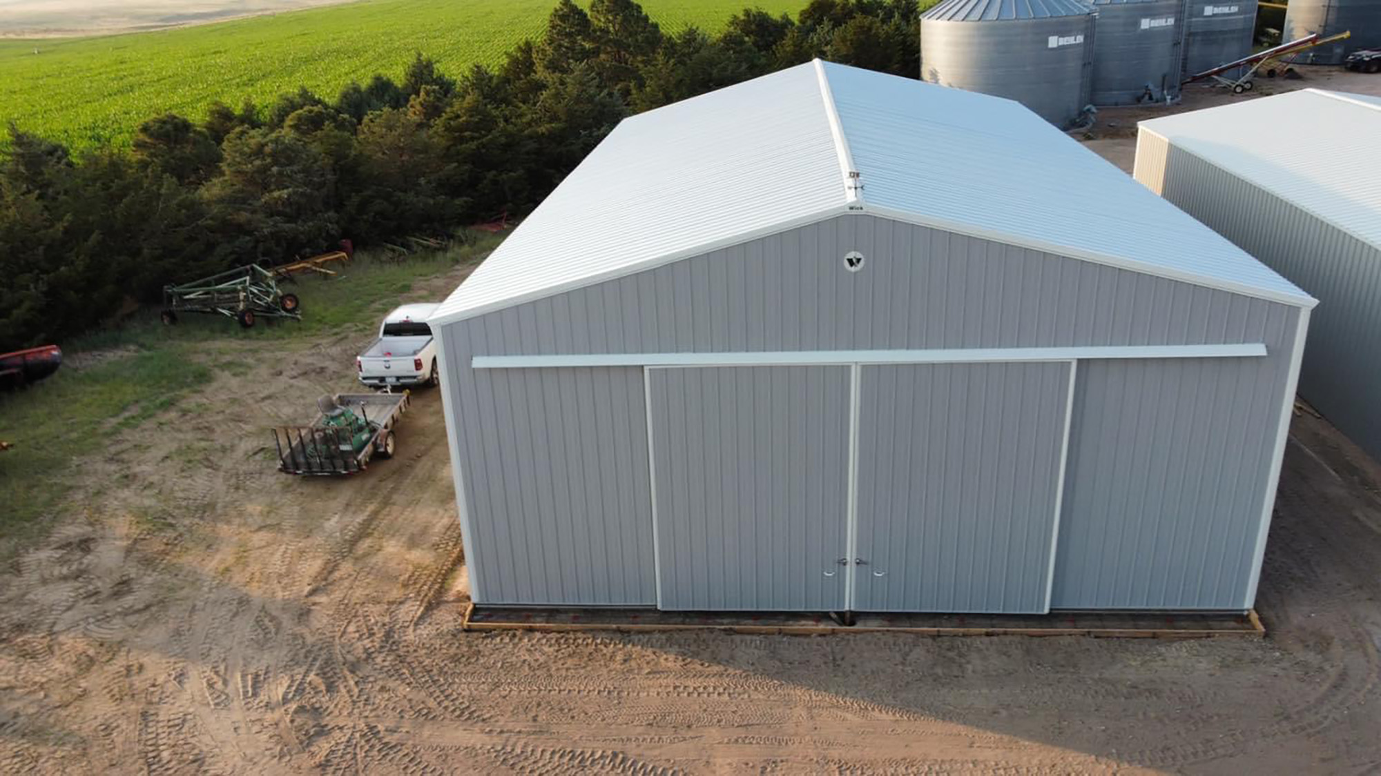 gray post frame agricultural building with white trim and featuring a large sliding door 